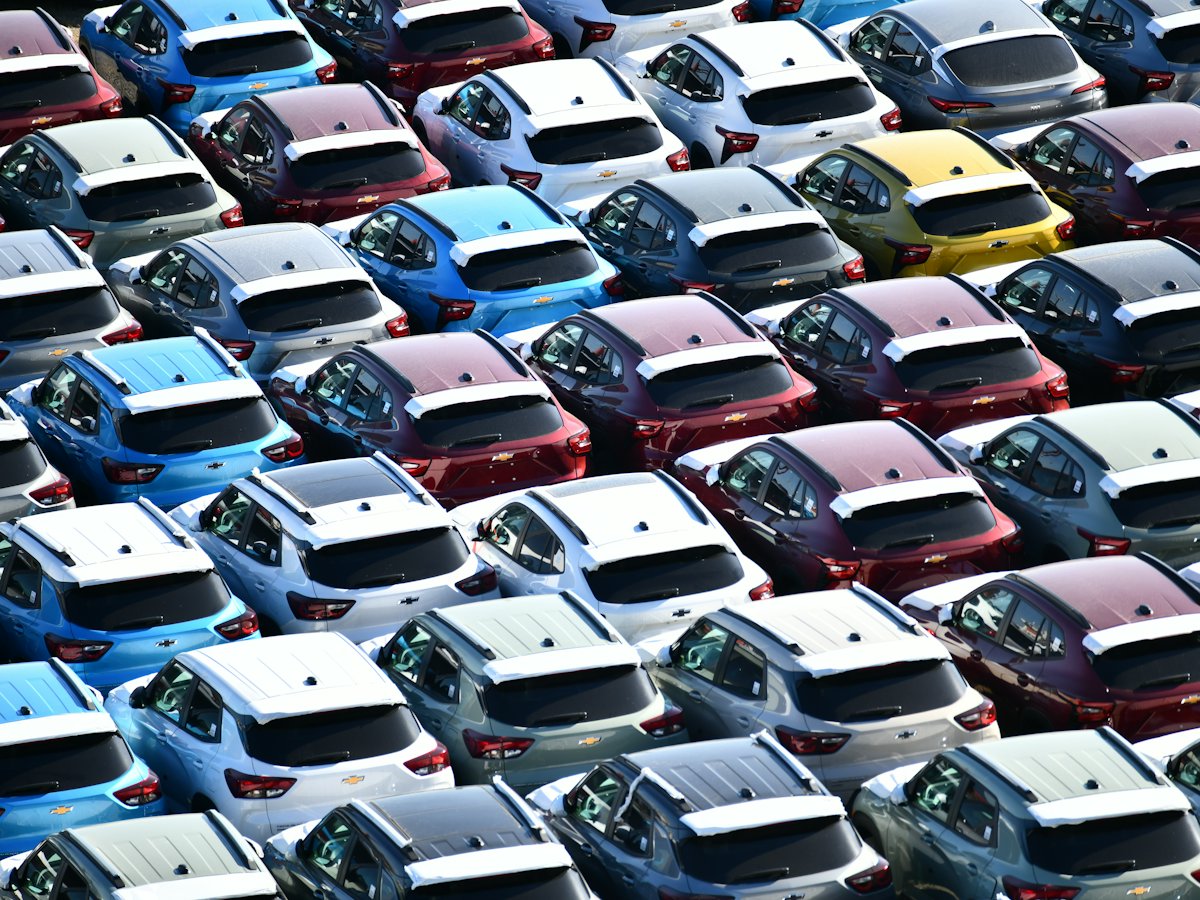 Rows of newly purchased cars lined up in a staging lot.